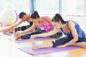 Fit class stretching legs on mats at yoga class