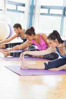 Fit class stretching legs on mats at yoga class