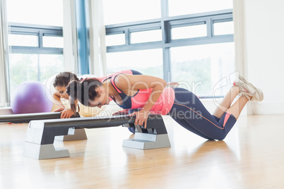 Two women performing step aerobics exercise in gym