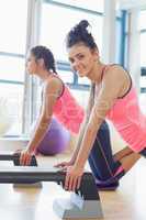 Two fit women performing step aerobics exercise