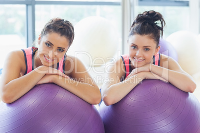 Two fit women with exercise balls at gym