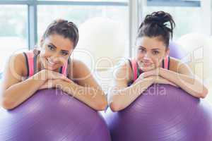 Two fit women with exercise balls at gym