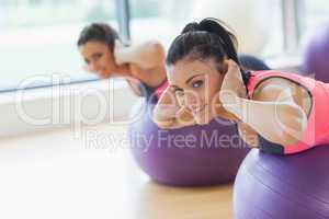 Portrait of two fit women exercising on fitness balls