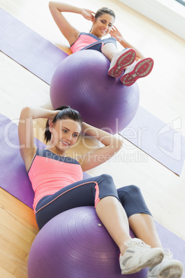 Two young women exercising with fitness balls at gym