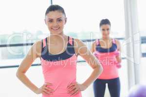 Smiling fit woman with friend in background at exercise room