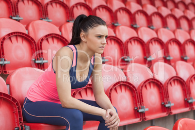 Serious toned young woman sitting on chair in the stadium