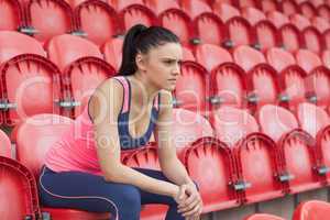 Serious toned young woman sitting on chair in the stadium