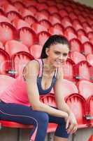 Smiling toned woman sitting on chair in the stadium