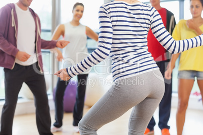 Mid section of fitness class and instructor doing pilates exerci