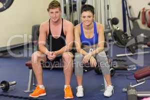 Sporty young man and woman sitting in the gym
