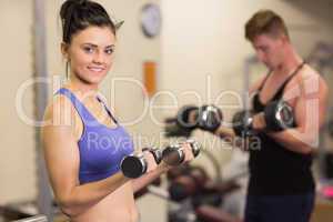 Young woman and man with dumbbells in gym