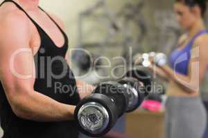 Man and woman using dumbbells in the gym