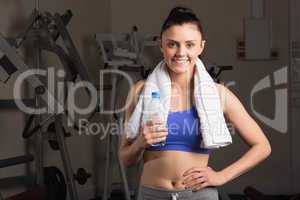 Smiling woman with water bottle standing in the gym