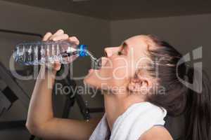 Close-up of a young woman drinking water in gym