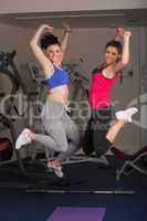 Two fit young women jumping in the gym