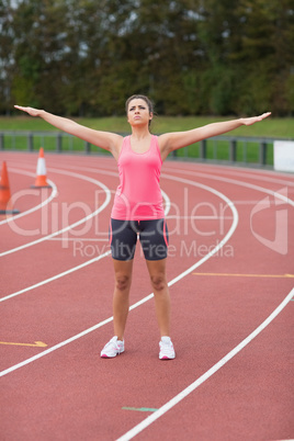Toned woman doing stretching exercise on the running track