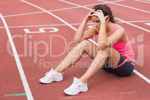 Young sporty woman sitting on the running track