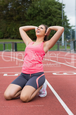 Toned woman doing stretching exercise on the running track