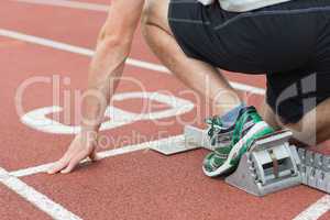 Mid section of a man ready to race on running track