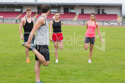 People stretching leg on grass against the stadium