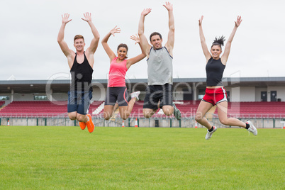 Fit people jumping on ground against the stadium