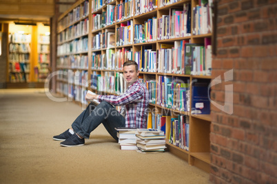 Smiling student sitting on library floor reading