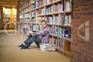 Smiling student sitting on library floor reading