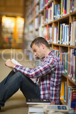 Focused student sitting on library floor reading Focused student sitting on library floor reading