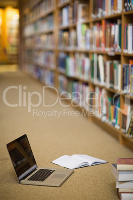 Laptop and books on the floor of library