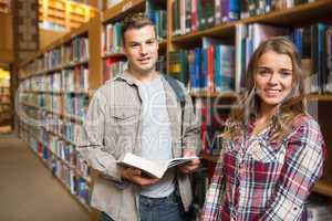 Happy classmates standing in library smiling at camera