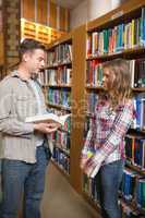 Happy classmates standing in library talking