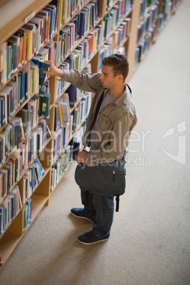 Student taking a book from shelf in library Student taking a book from shelf in library