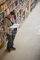 Student reading a book standing in library