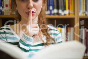 Redhead student asking for silence holding a book