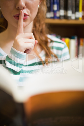 Student asking for silence holding a book