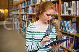 Focused student using tablet standing in library