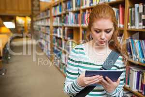 Serious student using tablet standing in library