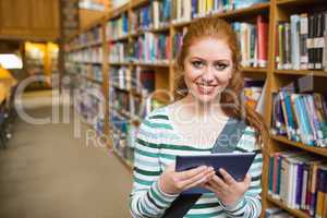 Cheerful student using tablet standing in library