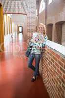 Happy student smiling at camera in the hall holding folders