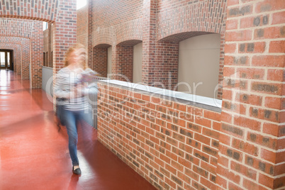 Young student walking in the hall holding folders