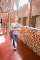 Young student rushing in the hall holding folders