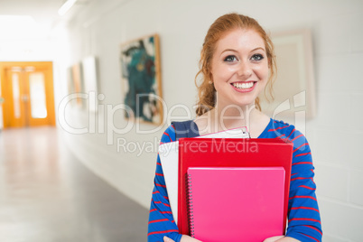Smiling student holding folders in the hall