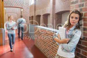 Student leaning against wall in the corridor looking at camera