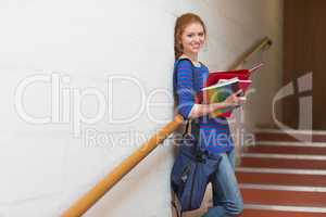 Smiling young student holding her notes on the stairs