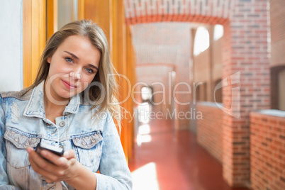 Happy student standing in the hall sending a text