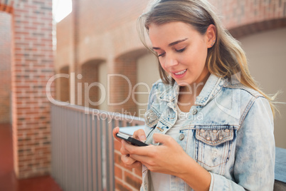 Smiling student standing in the hall sending a text