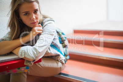Sad lonely student sitting on stairs looking at camera