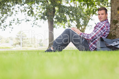 Happy student using his laptop to study outside
