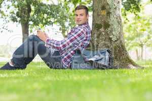 Smiling student using his tablet to study outside