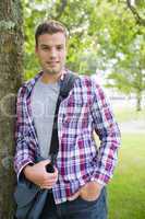 Handsome student leaning on tree looking at camera